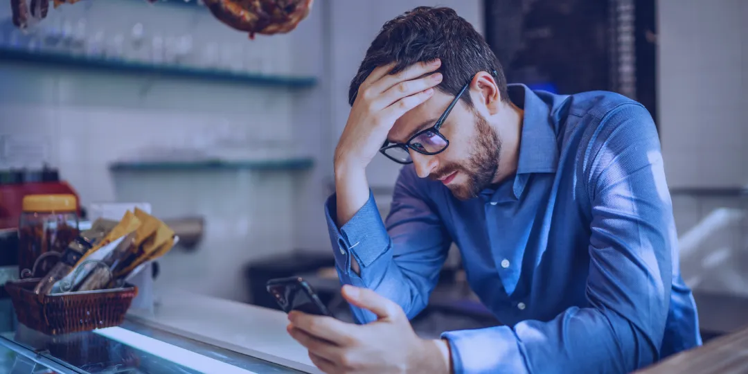 A photo of a person (could be a business owner or a marketer) sitting in front of a computer with a shocked or disappointed expression.